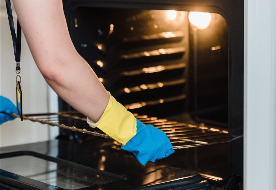 Person wearing gloves cleaning the inside of an oven